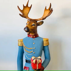 Decorative Christmas reindeer statue in a blue uniform holding a festive red gift, perfect for holiday home decor.