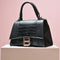 Luxury black crocodile leather handbag with golden clasp on display, showcasing high-end fashion accessory.